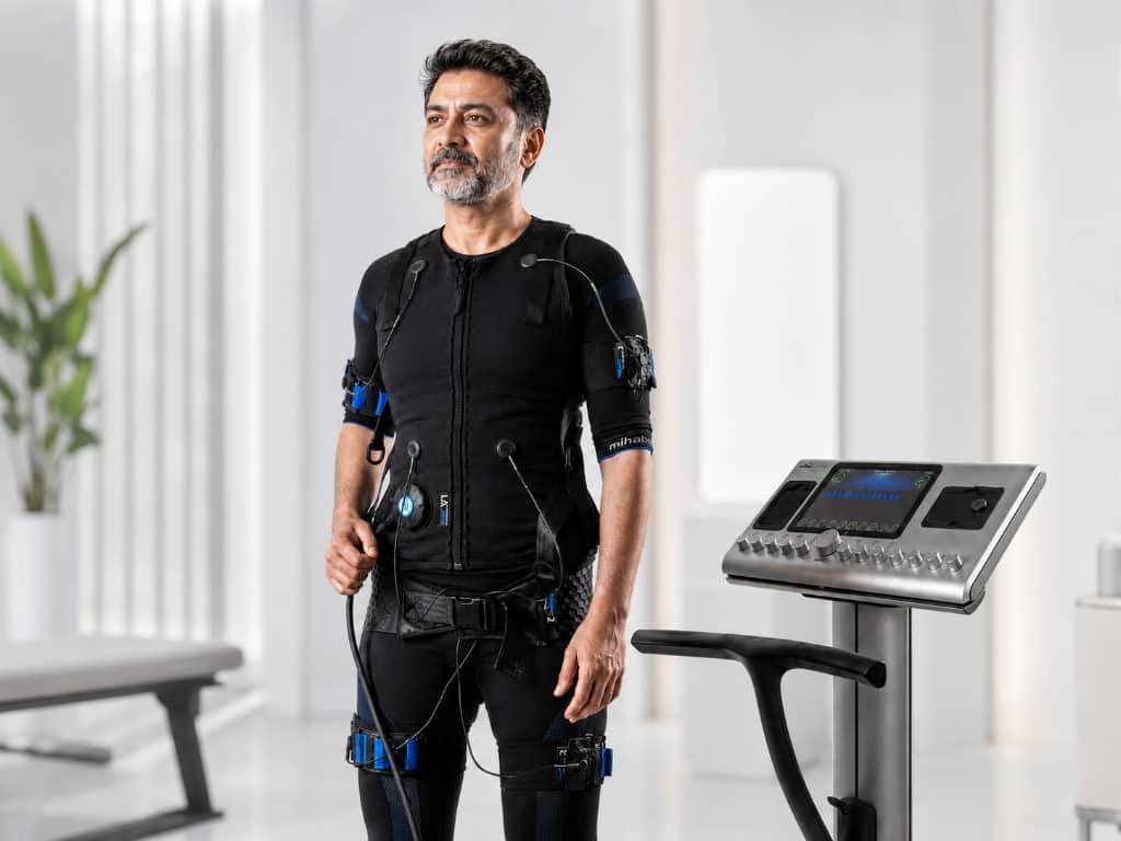 Man wearing EMS suit standing next to console