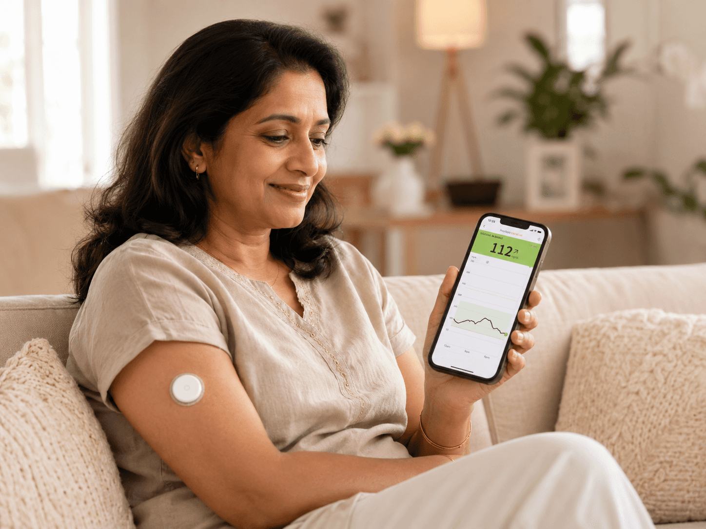 Woman wearing a CGM sensor and checking glucose data on her phone